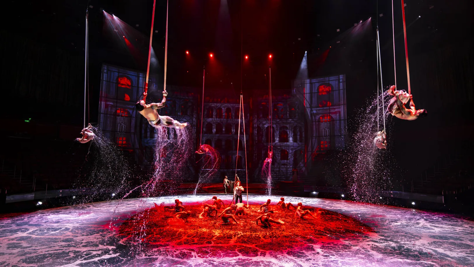 Red-lit aerial performers above the water stage in The House of Dancing Water